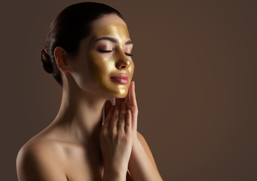 Model enjoying a luxury 24K Gold Facial treatment with glowing golden highlights on her face.