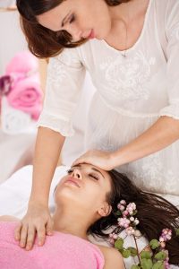 sideview of young messeur doing facial massage on young woman